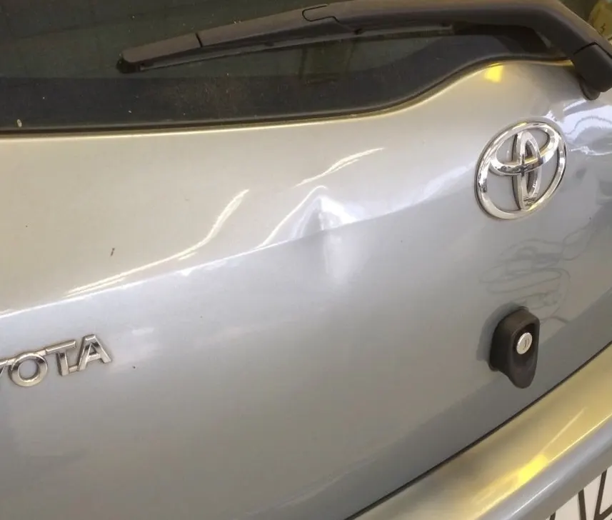 Il bagagliaio di un’auto grigia con un’ammaccatura